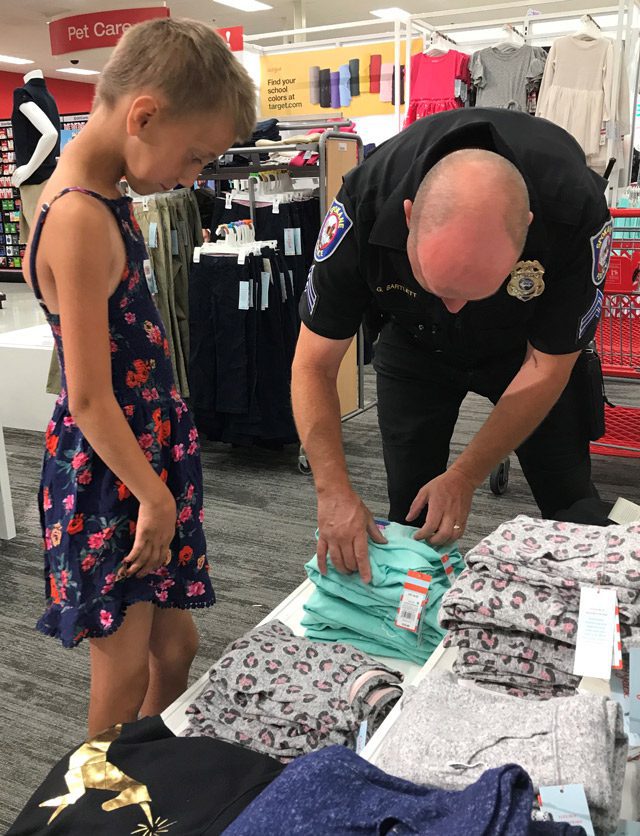 Officer helping young girl choose clothes