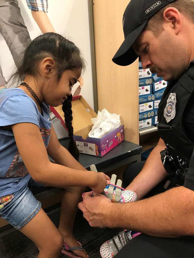 Officer helping young girl try on shoes